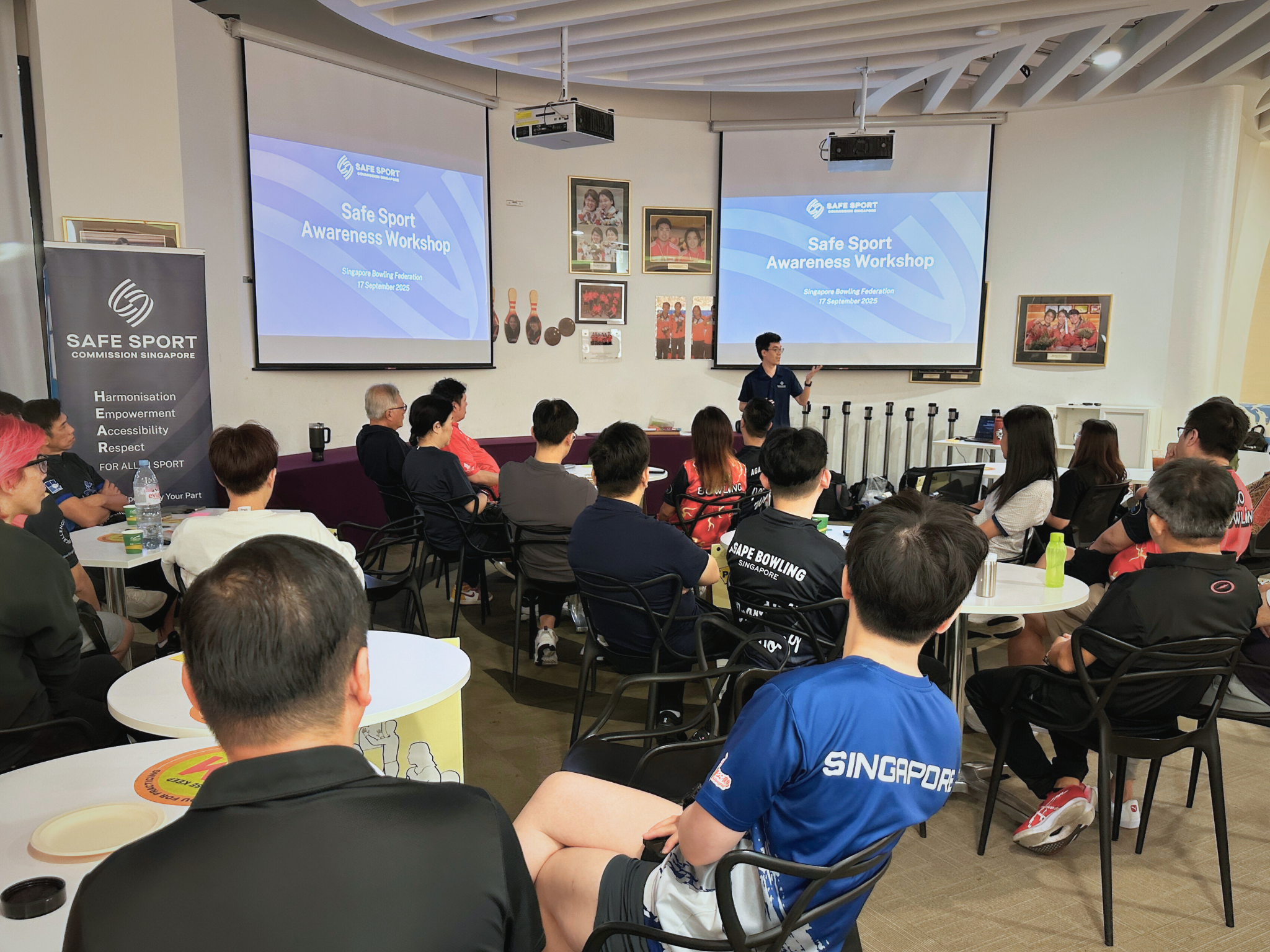 A man presents a presentation in front of a seated crowd